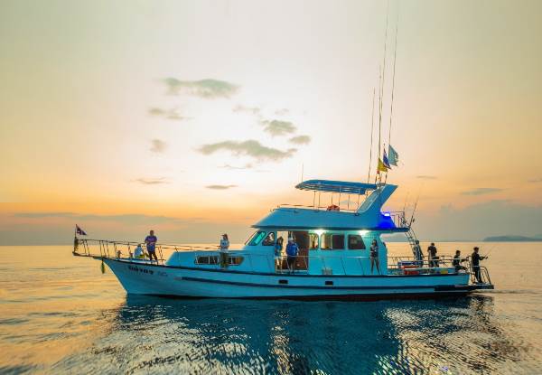 A boat gracefully sails across the ocean, illuminated by the warm hues of a stunning sunset.