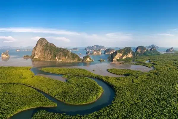 Traditional longtail boat with passengers on a serene river in Phang Nga Bay.