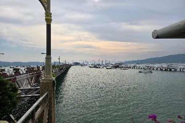 Ao Chalong Pier in Phuket with many sailboats in the harbor and a picturesque view of the sea.