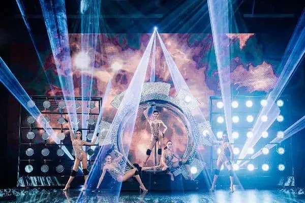 A vibrant stage at the Simon Cabaret Show in Phuket, featuring dancers illuminated by colorful lights.