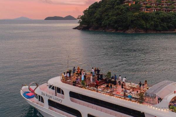 Silhouetted against a vibrant sunset, a boat with passengers floats peacefully on the water, creating a tranquil scene.