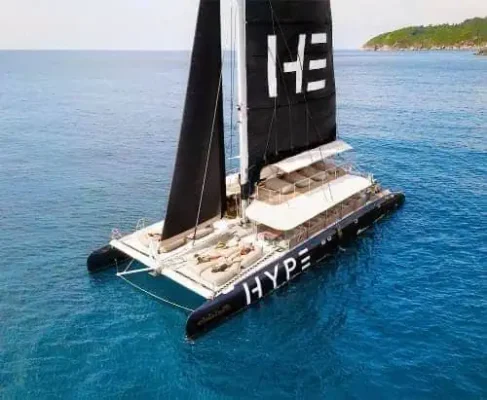 A catamaran featuring the word "hype" prominently displayed on its side, sailing on calm waters under a clear sky.