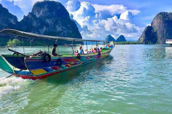 A boat carrying passengers glides smoothly down a serene river, surrounded by lush greenery.