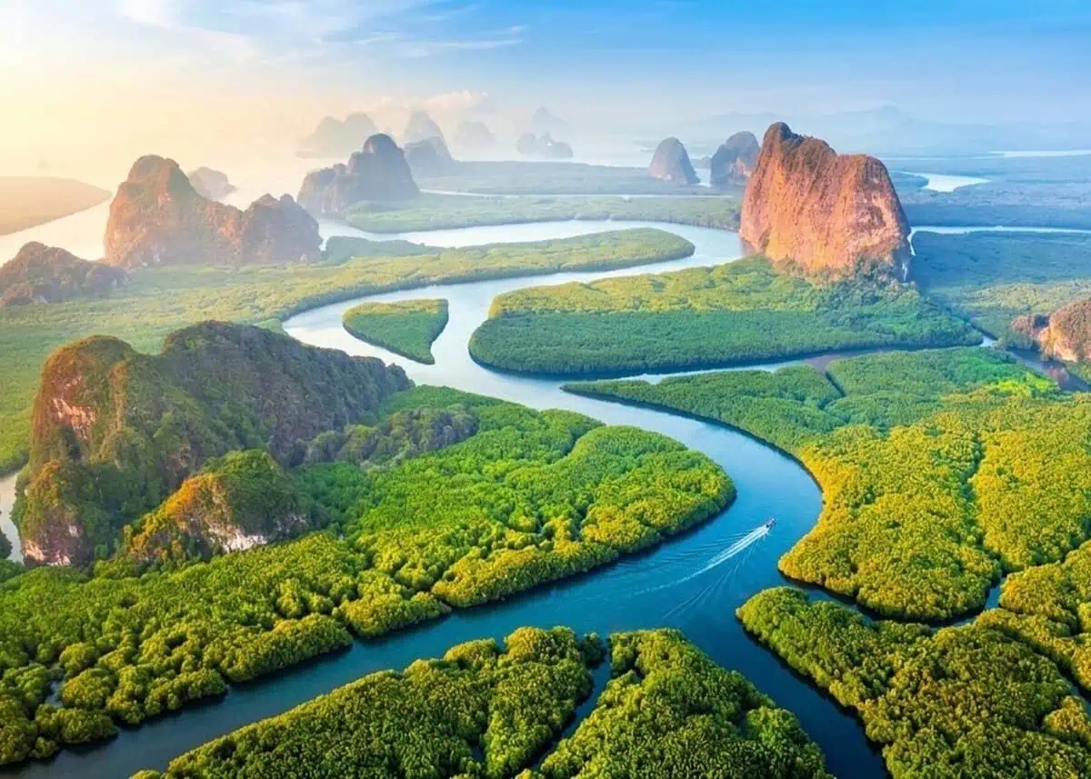 Traditional longtail boat with passengers crossing calm emerald water in Phang Nga Bay