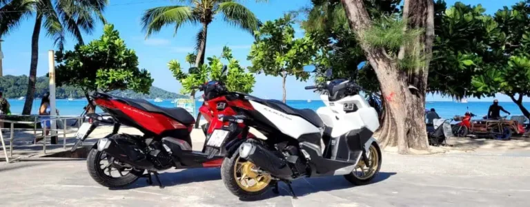 Two motorbikes parked on the sandy beach, with the ocean waves gently lapping in the background.