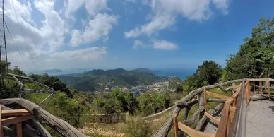 Rustic railing overlooking a green valley with a village, near Layan Beach.