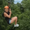 Rollerzipline Hanuman Phuket, Junge Frau mit Helm in Sicherheitsgurt, Dschungel